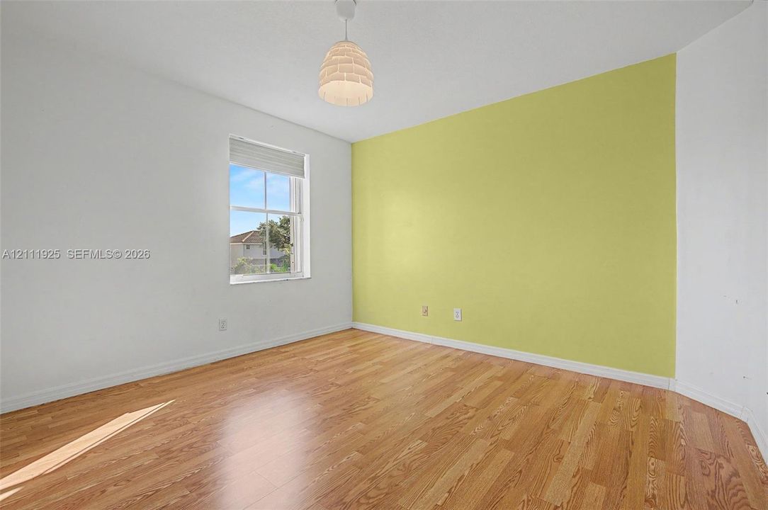 Room featuring wood-finish flooring, a single double-hung window, and a white dome pendant light fixture
