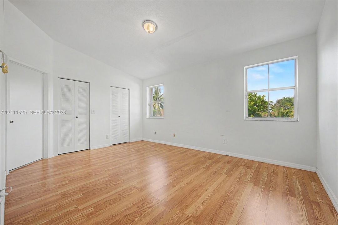 Interior space featuring wood-finish flooring, two sets of louvered closet doors, and dual windows