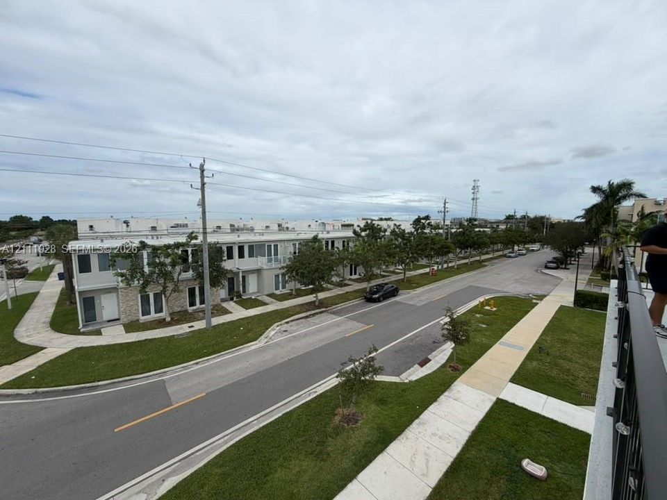 Exterior aerial perspective featuring multi-story residential structures with stone veneer accents, integrated balcony railings, concrete sidewalks, and landscaped grass buffers