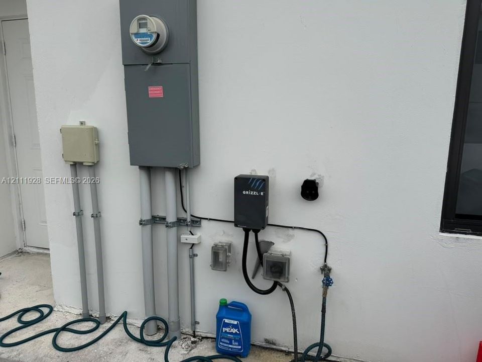 Exterior electrical panel with an integrated electric vehicle charging station and wall-mounted utility outlets