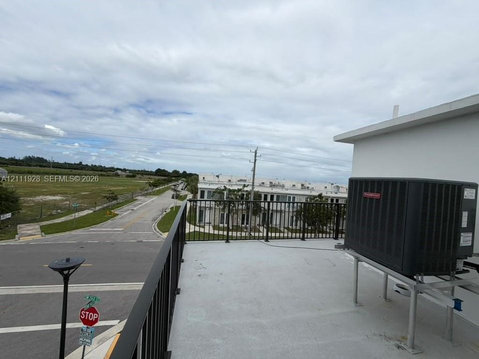 Rooftop terrace featuring a flat surface, metal railing, and external HVAC unit