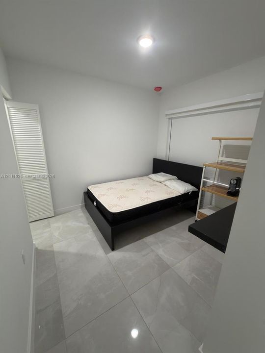 Neutral-toned, large-format tile flooring and a white louvered-door closet