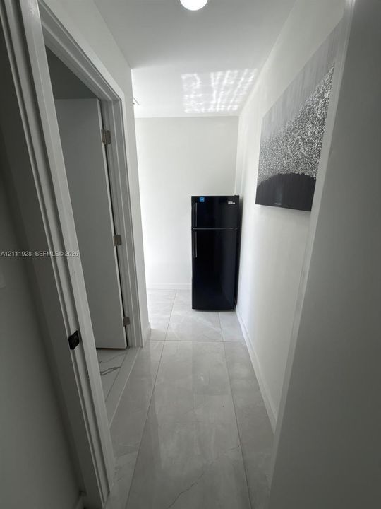 Large-format tile flooring, flush-mount ceiling lighting, and solid-core interior doors with matte black hardware