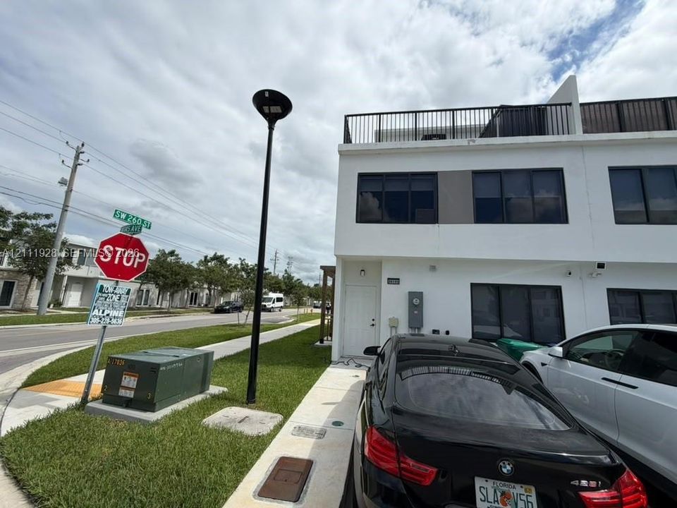Modern exterior featuring smooth white stucco finish, flat roofline, and rooftop terrace with metal railing