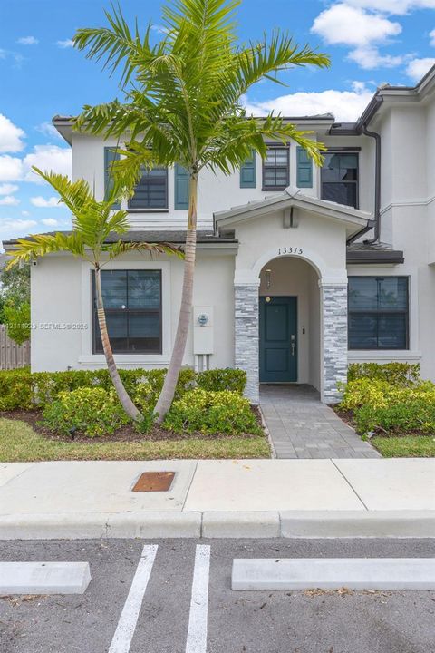 Stucco exterior featuring arched entryway, stone-veneer accents, shutters, and paved walkway