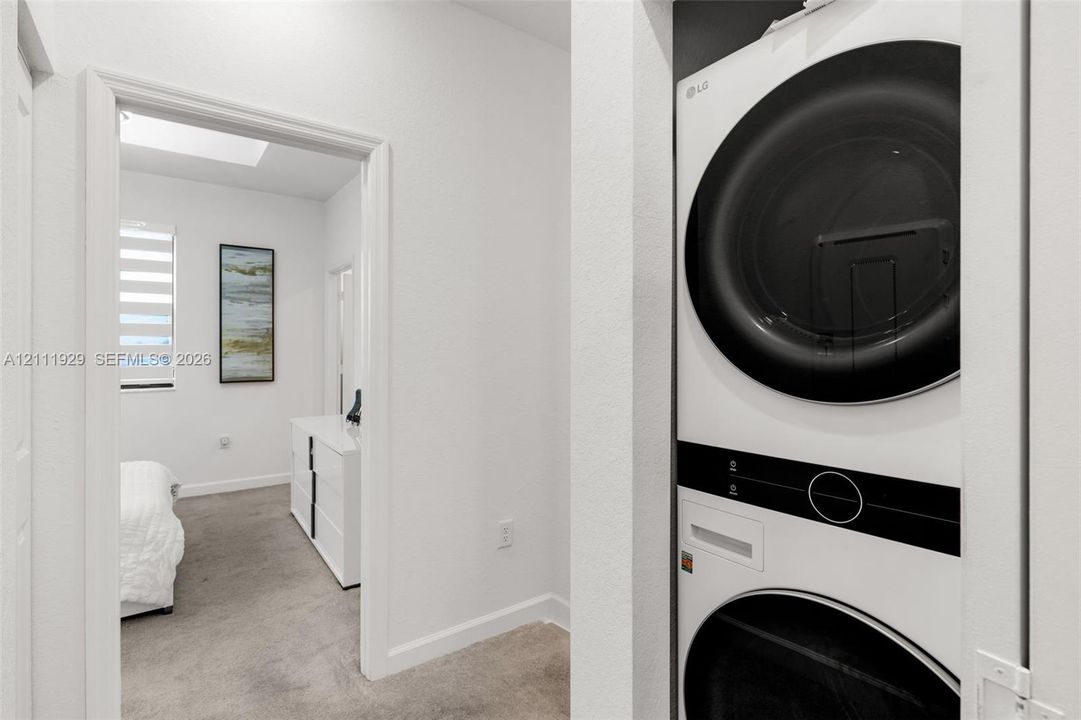 Stacked laundry unit with black circular trim set within a dedicated closet
