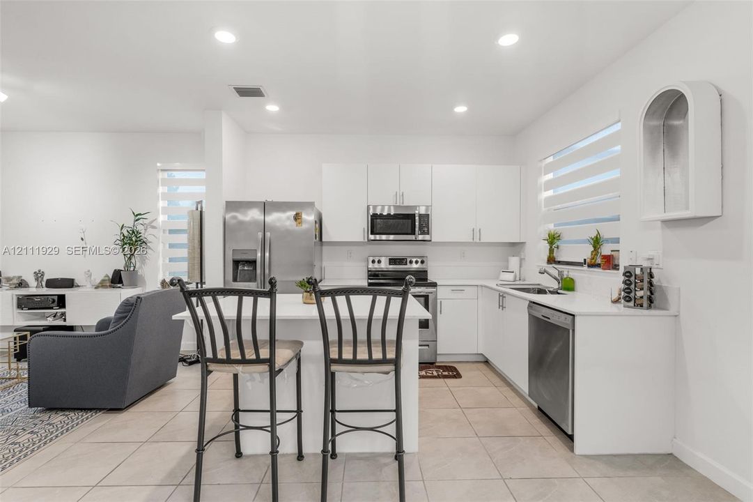 Kitchen featuring white flat-panel cabinetry, a central island, stainless steel appliances, recessed lighting, and tile flooring
