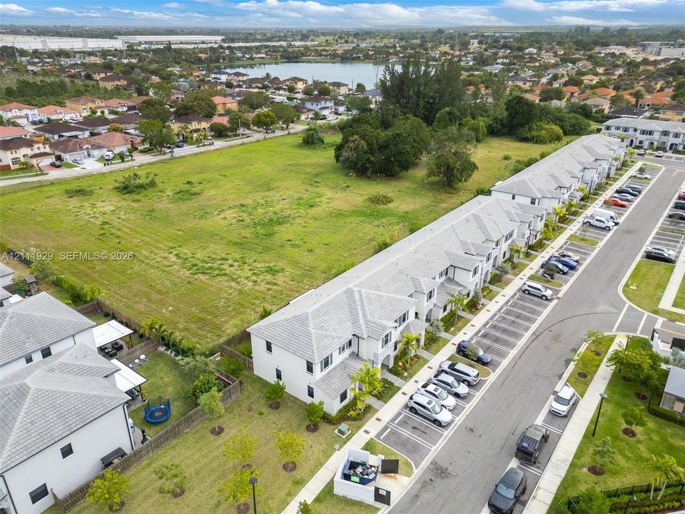 Aerial perspective of a multi-unit residential structure featuring a light-toned exterior, concrete tile roofing, and designated surface parking