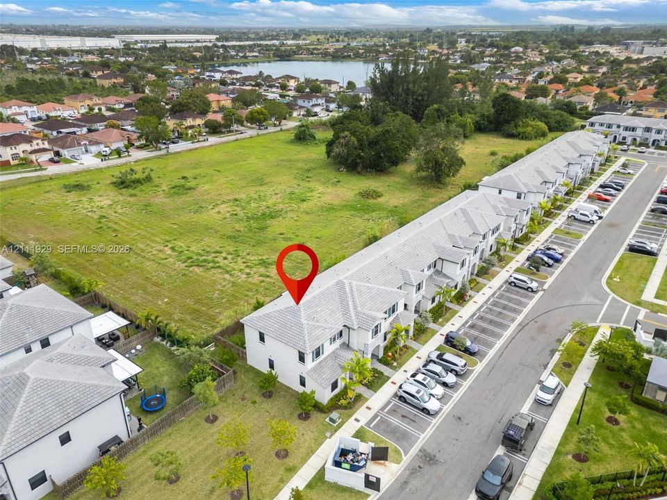 Aerial perspective of multi-unit residential structure featuring a light-toned tiled roof, neutral-colored stucco exterior, and dedicated surface parking