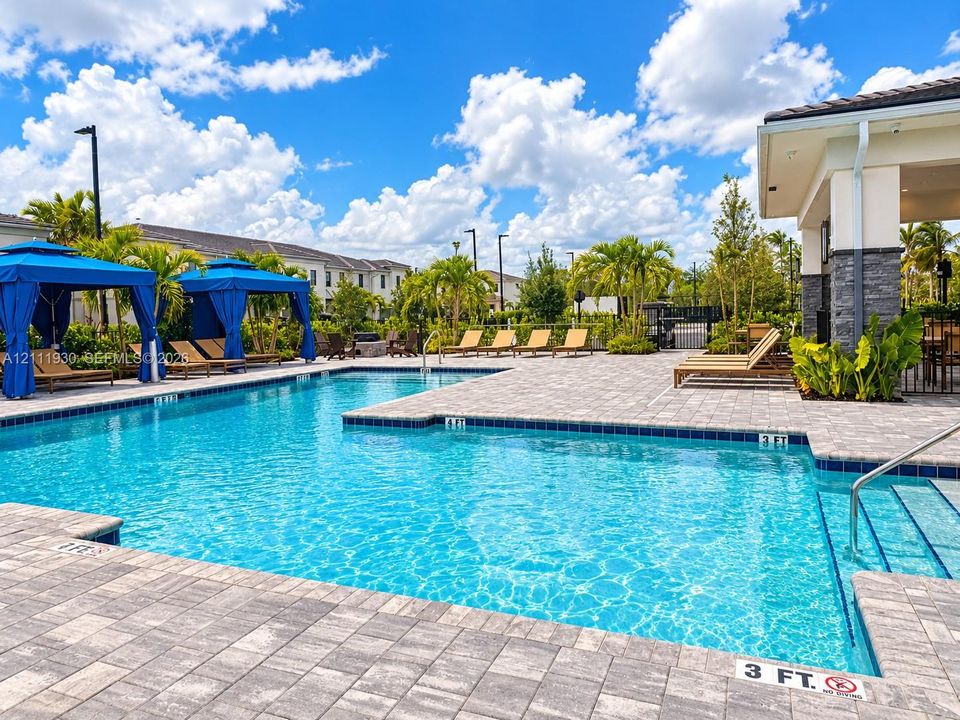 Swimming pool with stone paver decking, built-in structural cabanas, and integrated stair entry