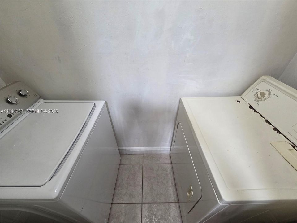 Dedicated laundry area featuring ceramic tile flooring and white appliances