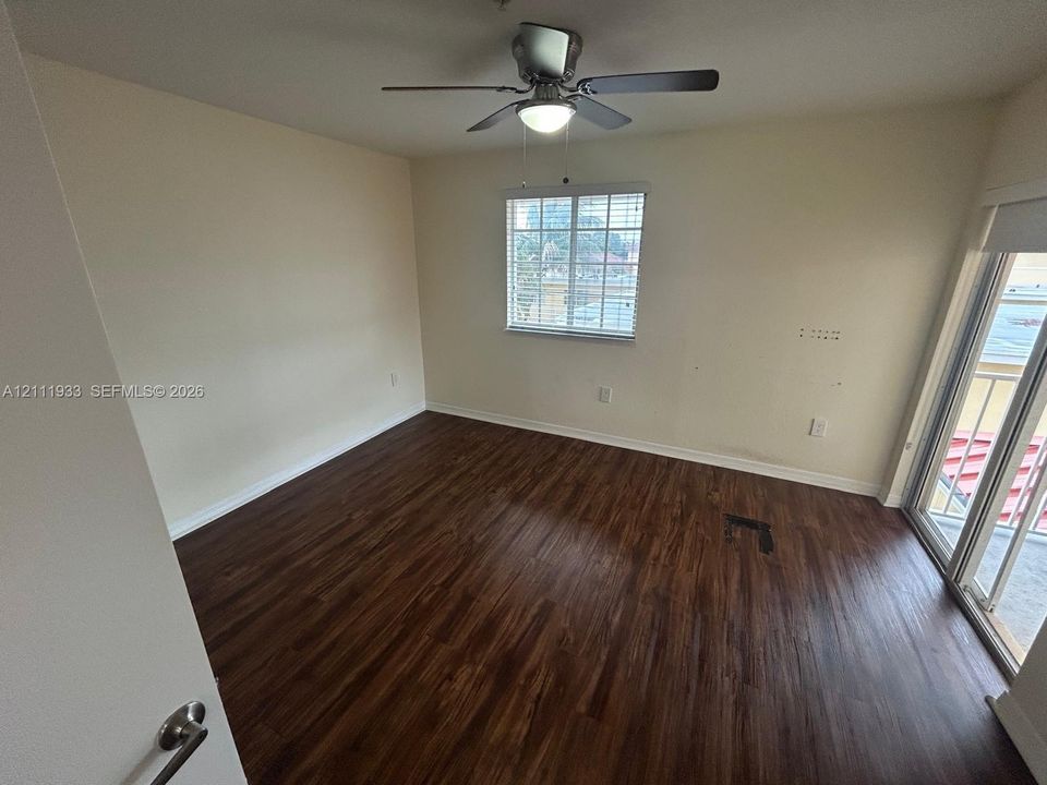 Room featuring wood-finish flooring, ceiling fan with integrated lighting, single-pane window with blinds, and sliding glass door