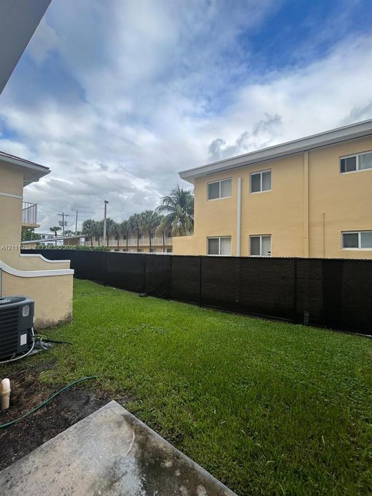 Private backyard featuring a manicured lawn, concrete patio, and full-perimeter black privacy fencing