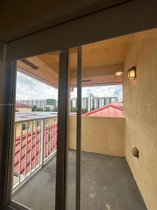 Covered balcony featuring a concrete floor, white metal railing, and wall-mounted exterior lighting