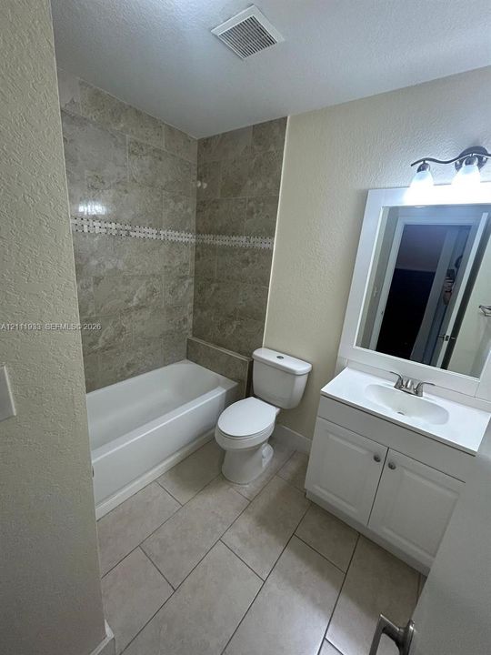 Bathroom featuring a vanity with a white cabinet, a white integrated sink, and an attached vanity mirror with overhead lighting