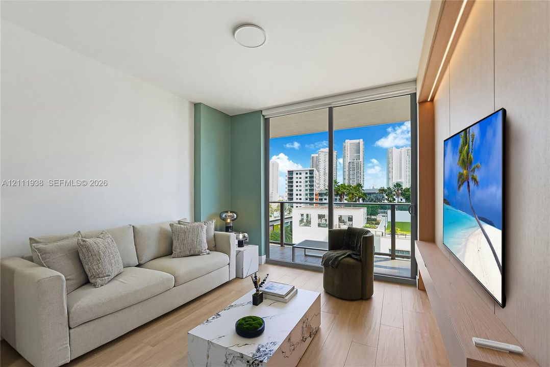 Floor-to-ceiling sliding glass door, built-in recessed media wall with integrated lighting, wood-finish flooring, and balcony with metal railing
