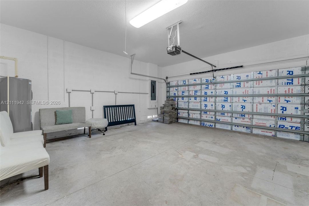 Two-car garage featuring insulated overhead door panels, exposed wall-mounted electrical conduit, concrete flooring, and an automated garage door opener