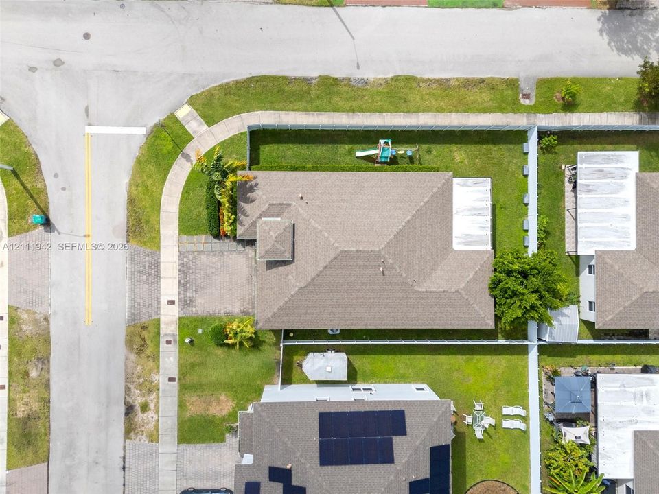 Corner lot with a paved driveway, exterior hardscaping, and a fenced yard