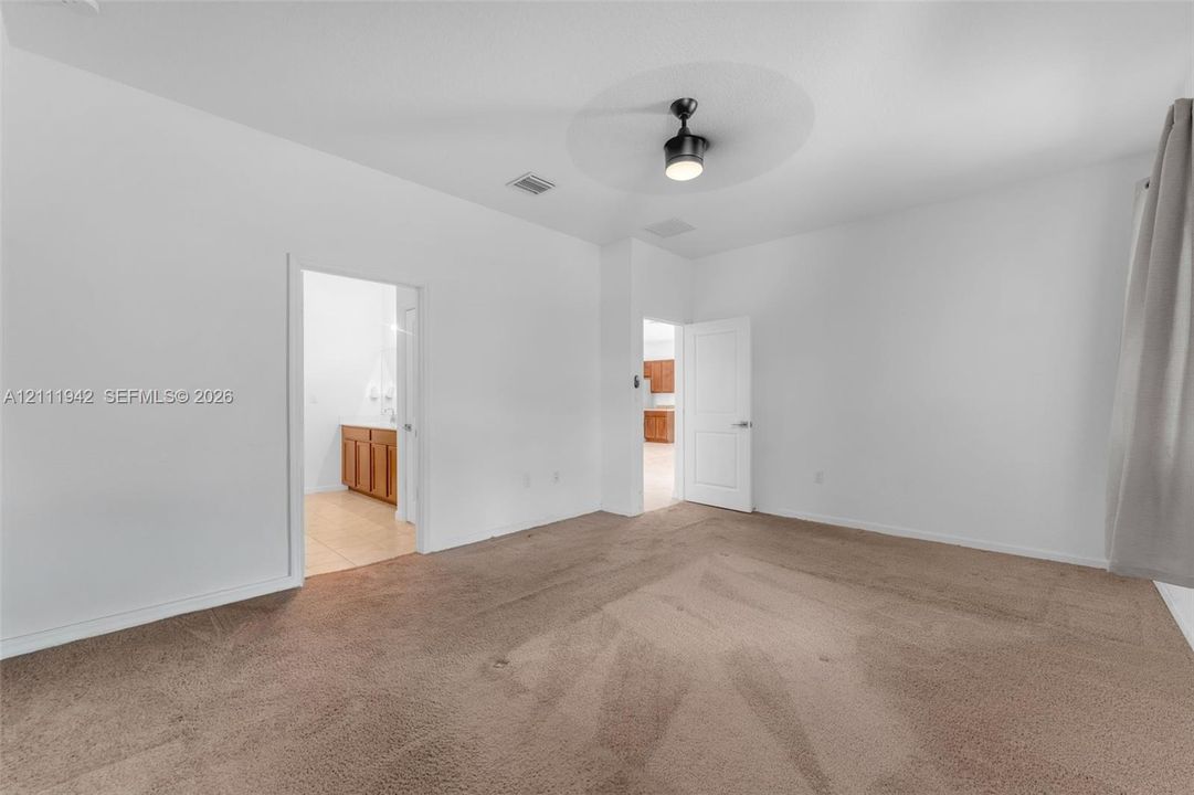 Room featuring wall-to-wall carpeting, a multi-blade ceiling fan with an integrated light fixture, and two interior doors