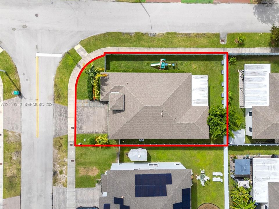 Corner lot featuring a fenced backyard, paved driveway, hip roof, and mature perimeter landscaping