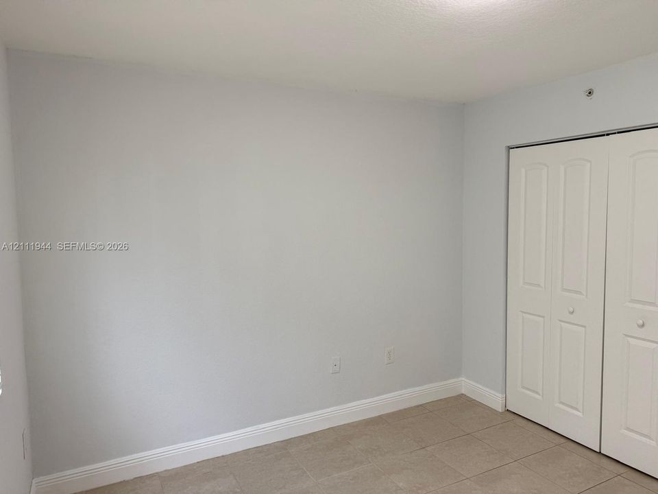 Neutral-toned interior space featuring light-colored tile flooring and double-panel closet doors