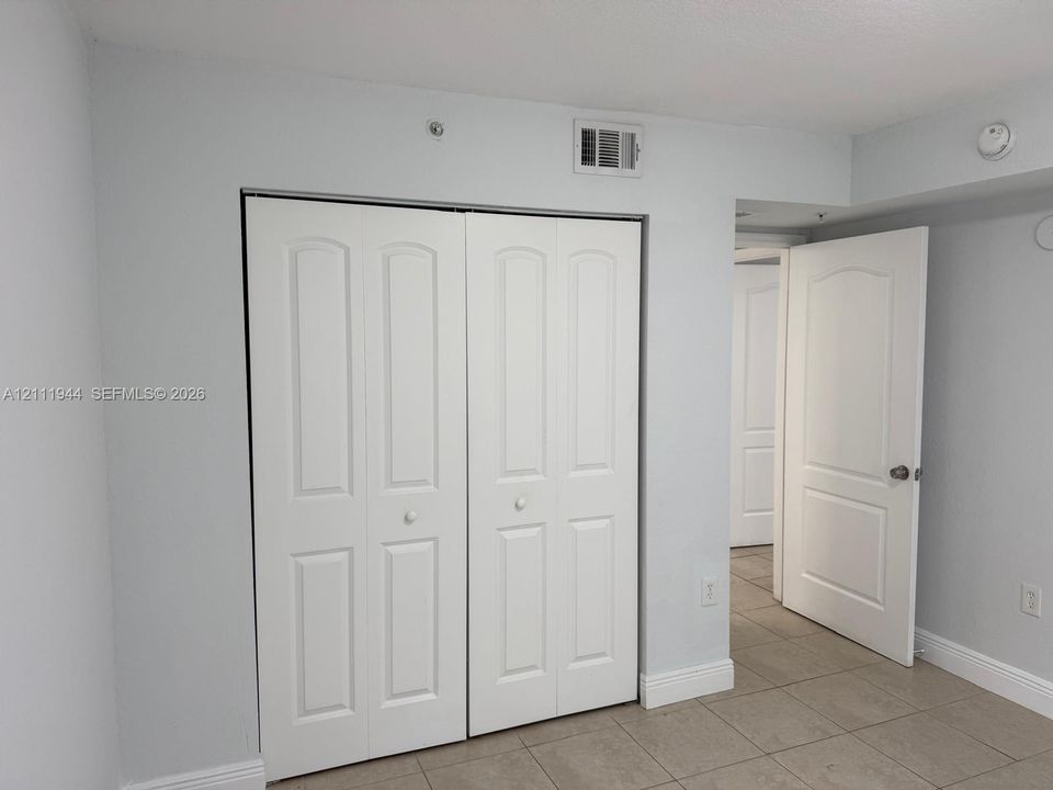 Neutral-toned room featuring tiled flooring, a double-panel closet with white doors, and a matching six-panel interior door
