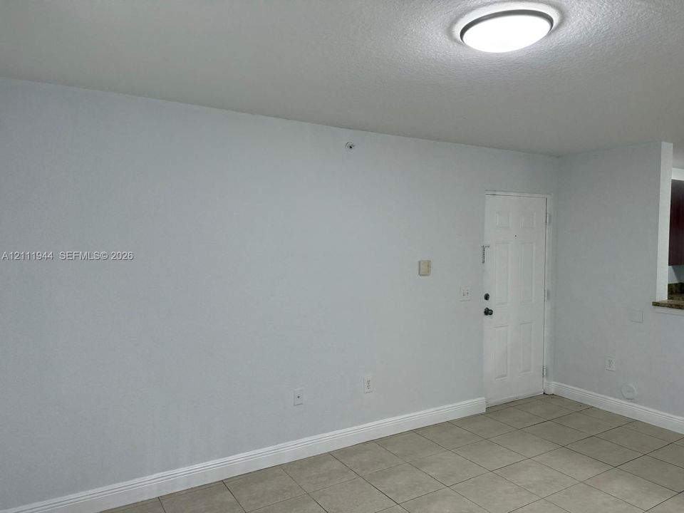 Neutral-toned ceramic tile flooring, solid-panel entry door, and flush-mount ceiling lighting