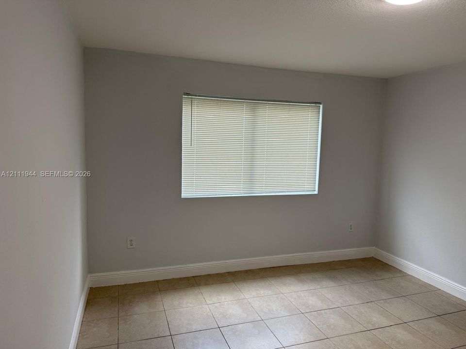 Neutral-toned walls, tile flooring, and a window with horizontal blinds