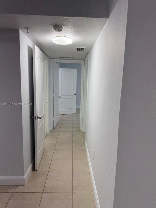 Hallway featuring ceramic tile flooring, neutral painted walls, and multi-panel interior doors with metallic hardware