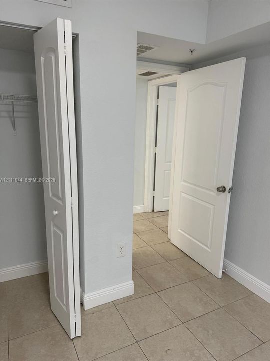 Ceramic tile flooring, interior doors with arched panel detailing, and wire closet shelving