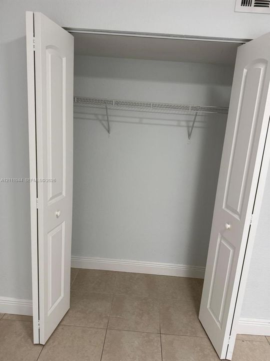 Closet featuring white paneled bifold doors, tile flooring, and integrated wire shelving with a clothes rod