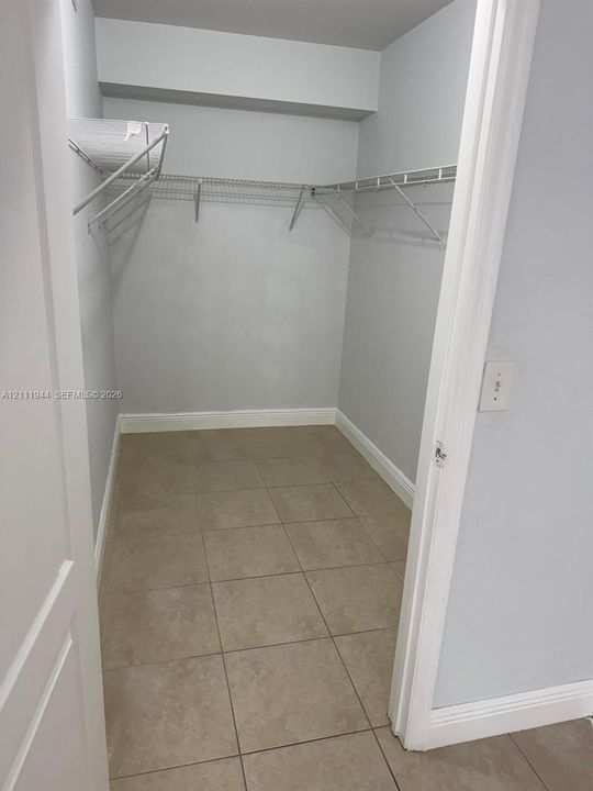 Walk-in closet featuring ceramic tile flooring, neutral painted walls, and integrated wire shelving