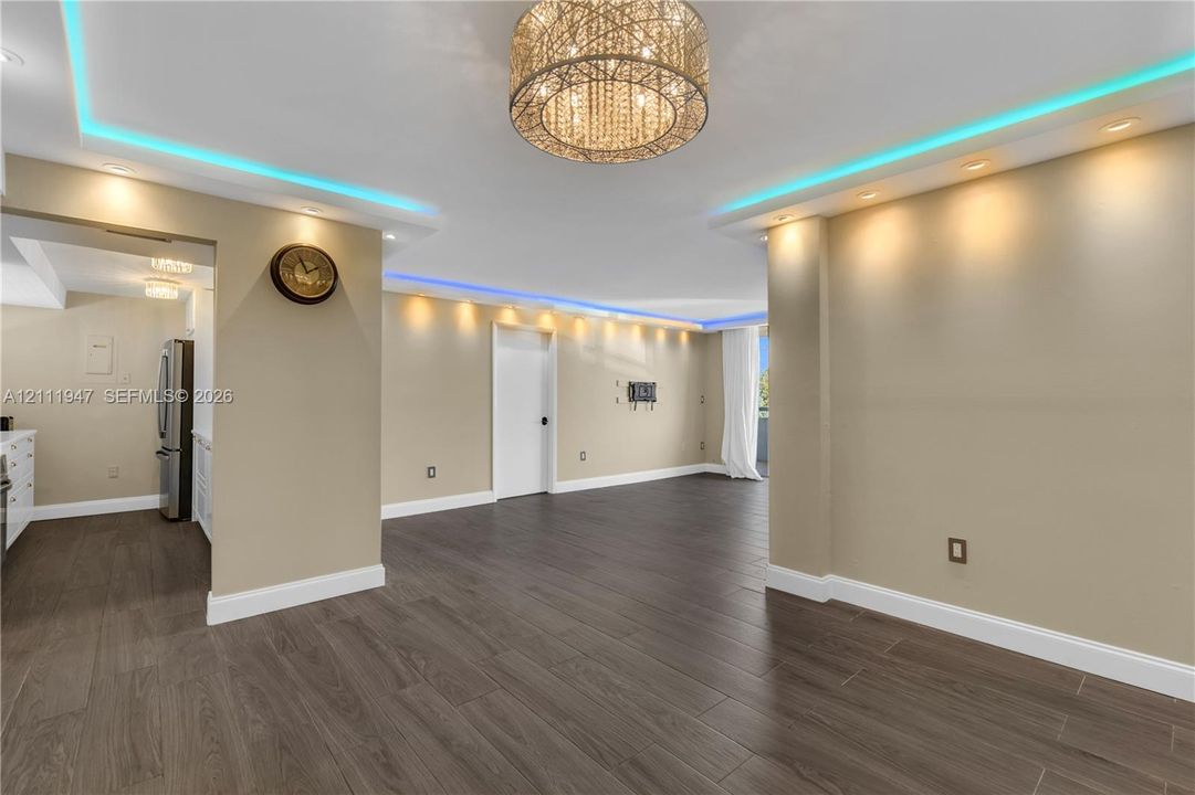 Wood-finish tile flooring, decorative drum chandelier, multi-level tray ceiling with integrated recessed and perimeter accent lighting