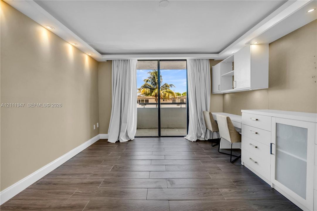 Wood-finish flooring, recessed ceiling lighting, built-in cabinetry, and sliding glass doors opening to a balcony