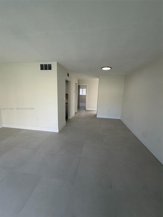 Neutral-toned interior featuring large-format ceramic tile flooring, recessed lighting, and a crisp, white-painted finish