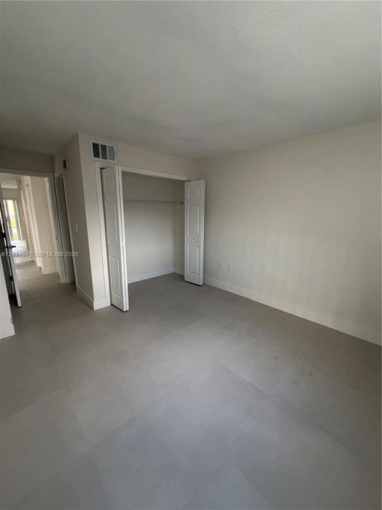 Room featuring neutral-toned floor tile and a reach-in closet with double-panel doors