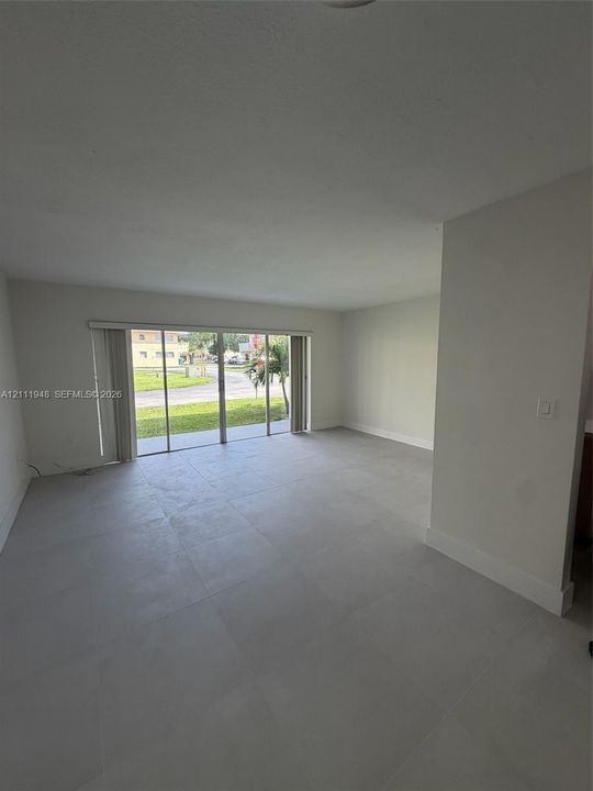 Open-concept interior featuring large-format tile flooring and floor-to-ceiling sliding glass doors