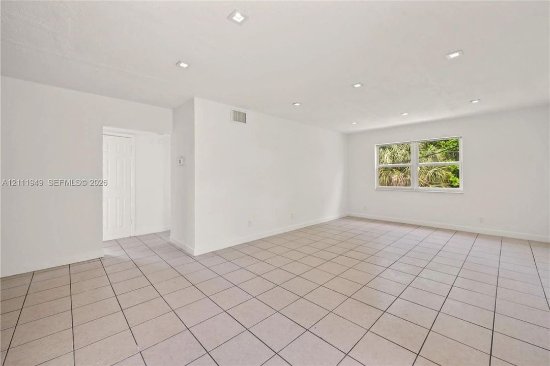 Open interior space featuring neutral ceramic tile flooring, recessed ceiling lighting, and a single-pane window
