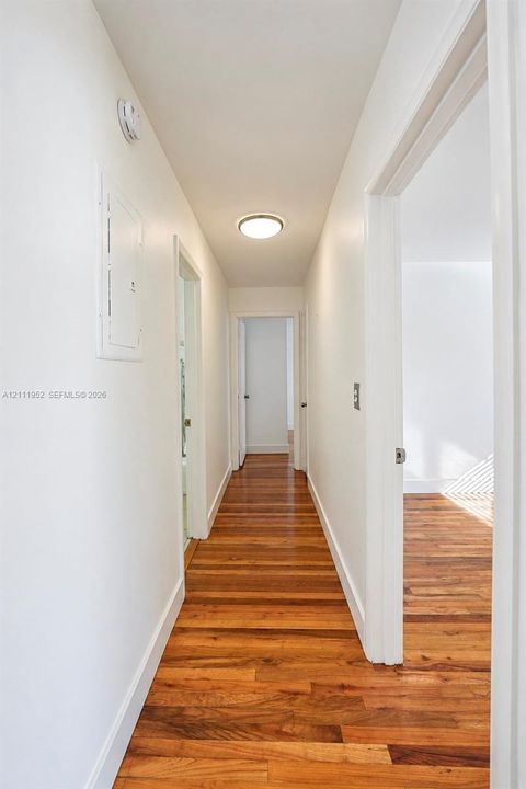Hallway featuring wood flooring, white walls, and flush-mount ceiling lighting