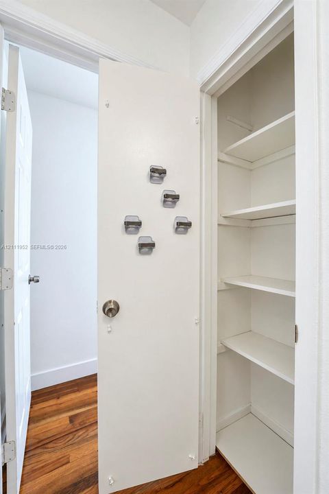 Built-in closet featuring multi-tiered shelving and wood-finish flooring