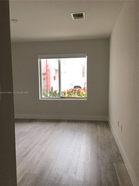 Neutral interior space featuring wood-finish flooring and a single-pane window