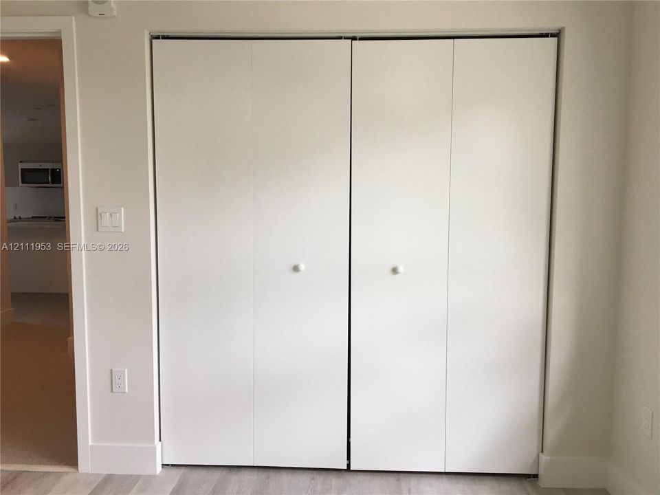 Bi-fold closet doors featuring a smooth white finish and spherical white hardware