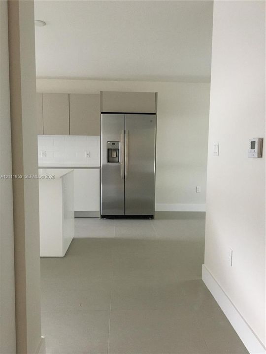 Kitchen featuring flat-panel cabinetry, stainless steel side-by-side refrigerator, solid-surface island, and large-format tile flooring