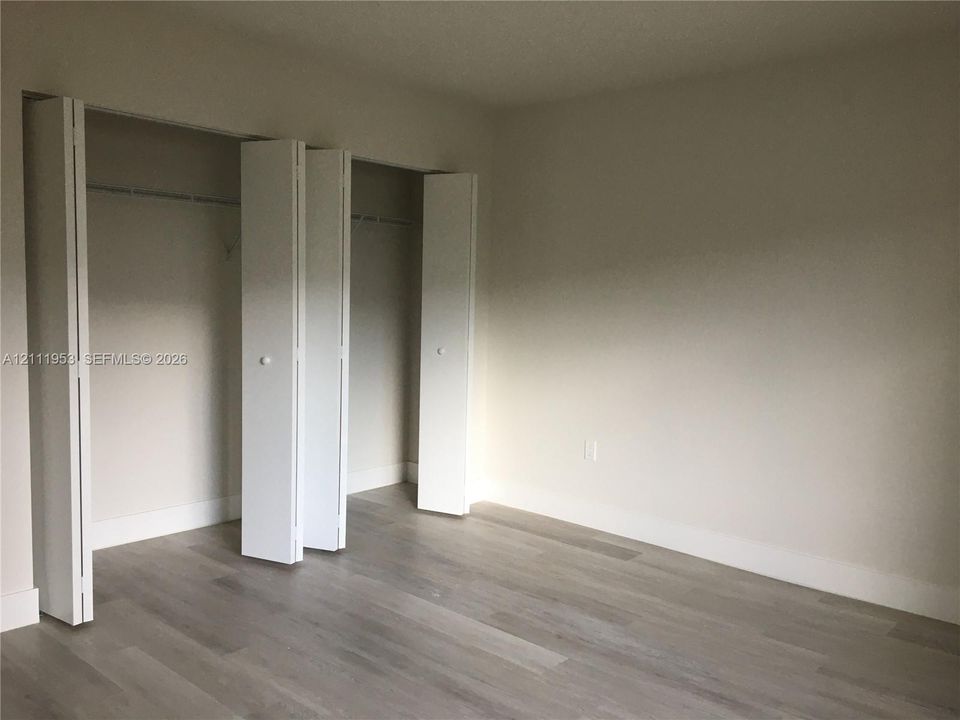 Wood-finish flooring and dual bi-fold door closets with overhead hanging rods