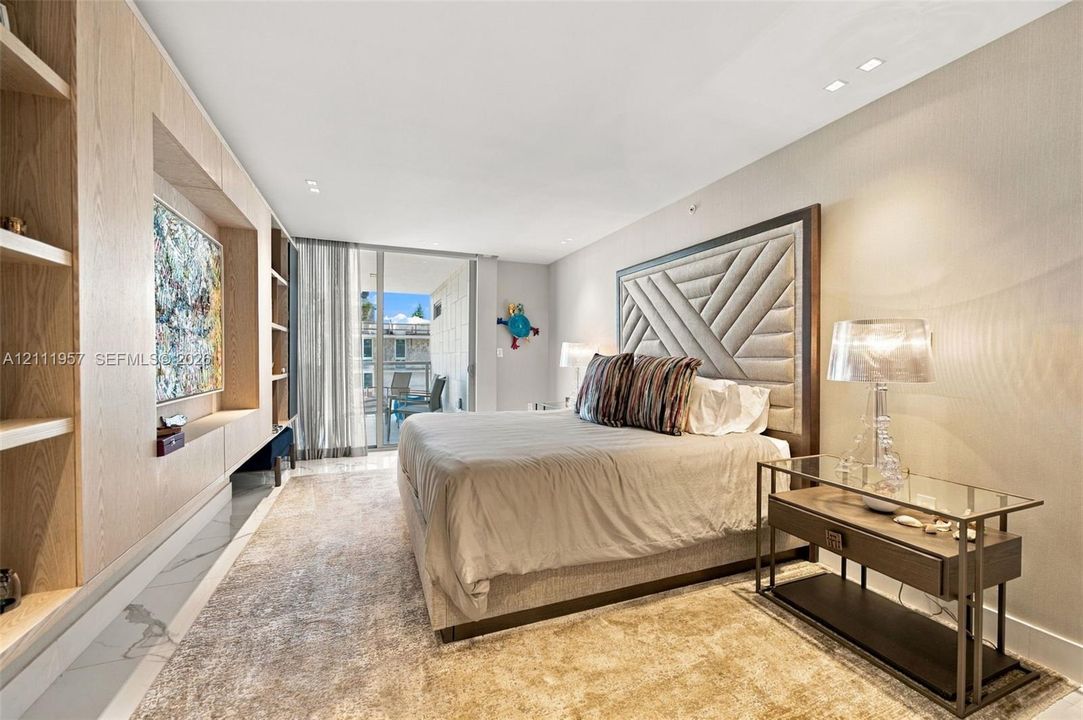 Custom built-in light wood cabinetry, recessed ceiling lighting, and glass sliding doors leading to an exterior balcony