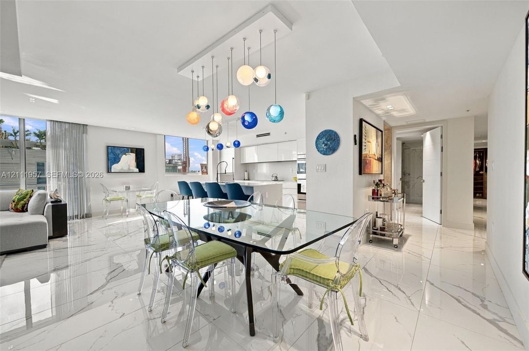 Large format tile flooring with high-gloss finish, multi-colored tiered glass globe chandelier, expansive floor-to-ceiling windows, and minimalist kitchen cabinetry