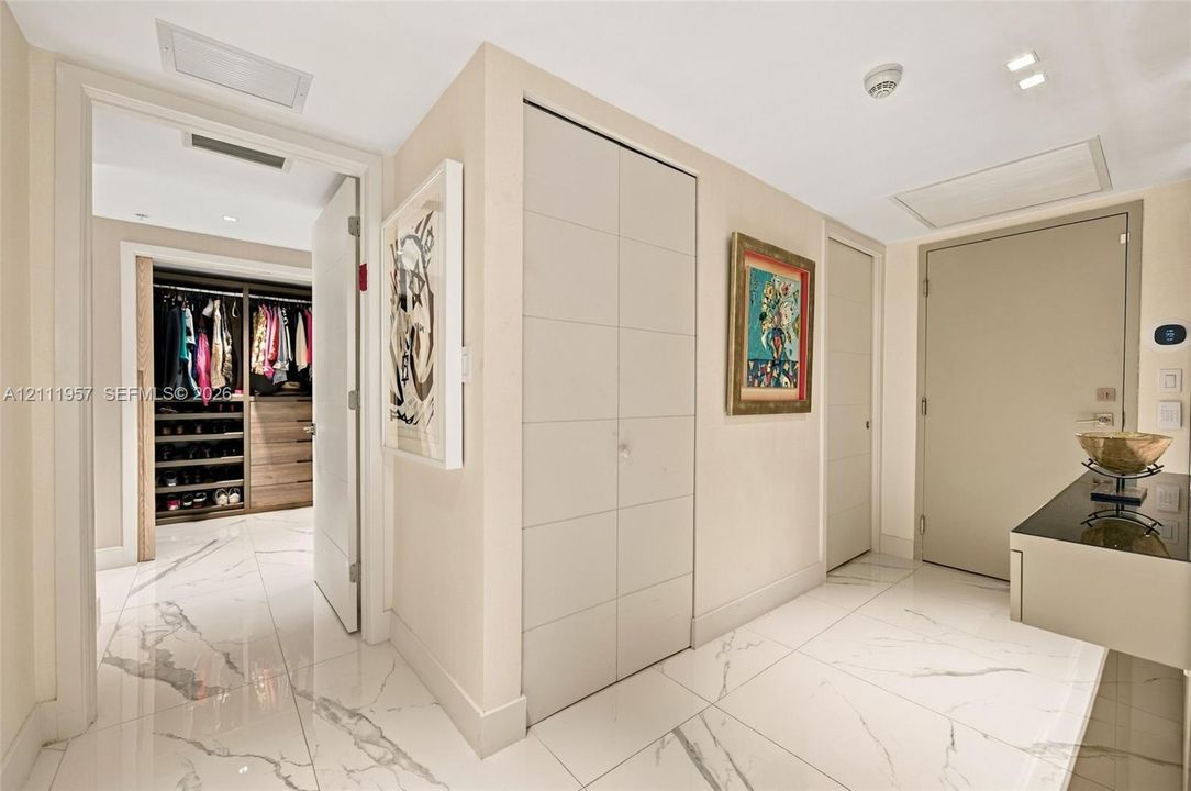Large-format tile flooring, built-in floor-to-ceiling cabinetry with panel detailing, and custom walk-in closet featuring wood-finish shelving and drawer units