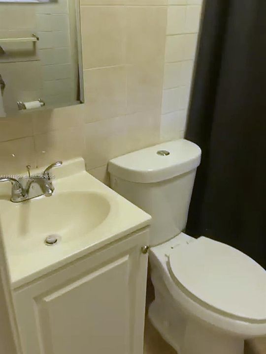 Bathroom featuring a white vanity cabinet with an integrated sink, dual-handle chrome faucet, wall-mounted medicine cabinet, and ceramic wall tiling
