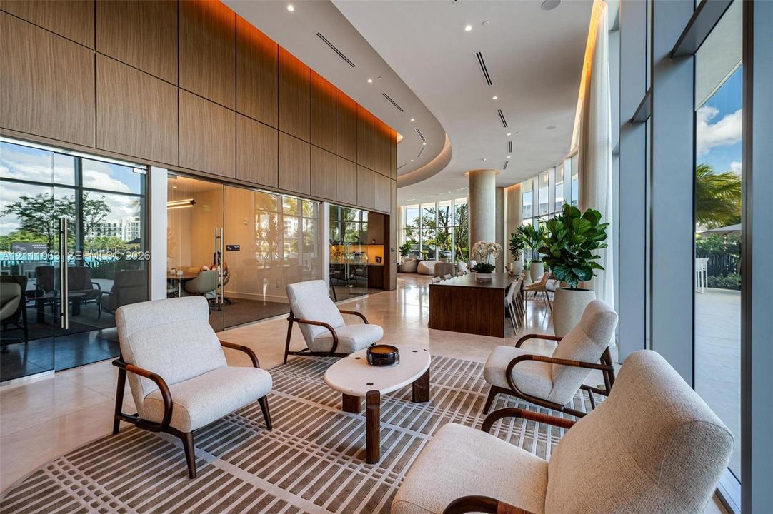 Expansive common area featuring floor-to-ceiling glass walls, integrated wood-paneled wall accents, recessed architectural lighting, and polished stone flooring