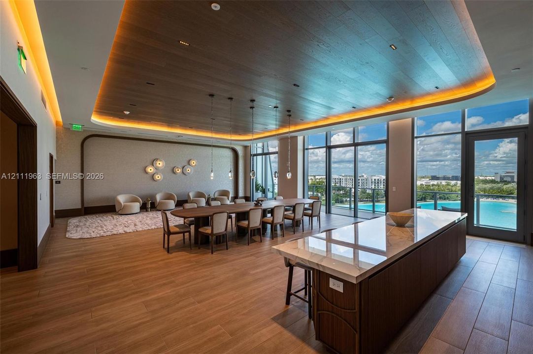 Expansive room featuring a wood-paneled ceiling with recessed cove lighting, floor-to-ceiling windows, wood-finish flooring, and a large island topped with a stone-finish countertop